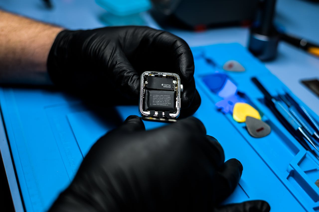 portfolio-02 Technician disassembling smartwatch with precision tools in a repair workshop.